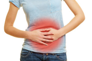 girl holding onto stomach with both hands due to abdominal pain