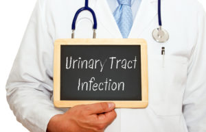 Urinary Tract Infection written on chalkboard held up by a male doctor